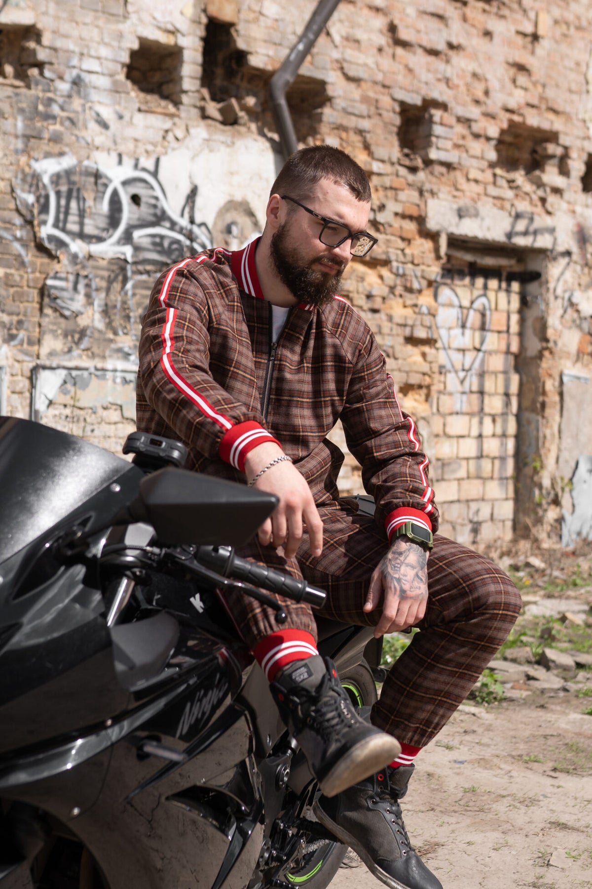 Premium Coffee Checkered Gentlemen Tracksuit — checkered bomber jacket and joggers, seated on a motorcycle