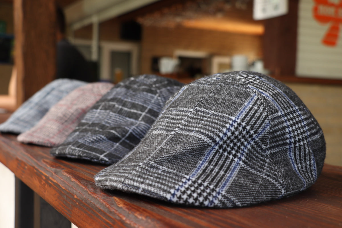 Grey Glen Plaid Flat Cap — on a table with other flat caps