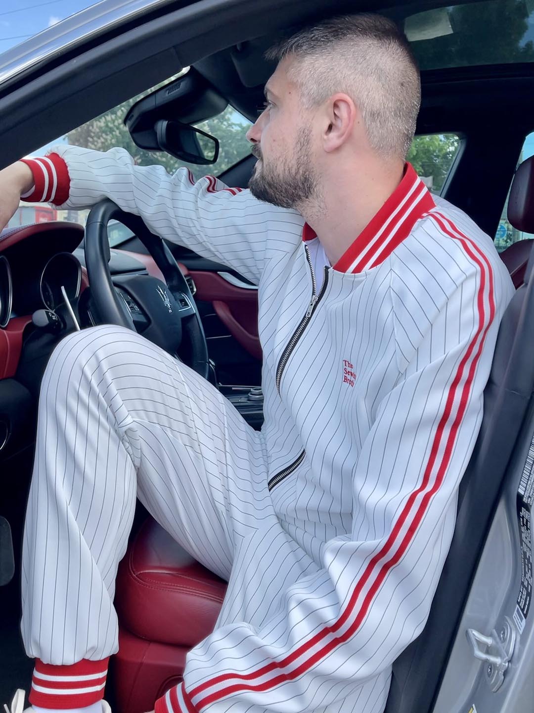 Premium White & Red Pinstripe Gentlemen Tracksuit — pinstripe bomber jacket and joggers, seated in a car