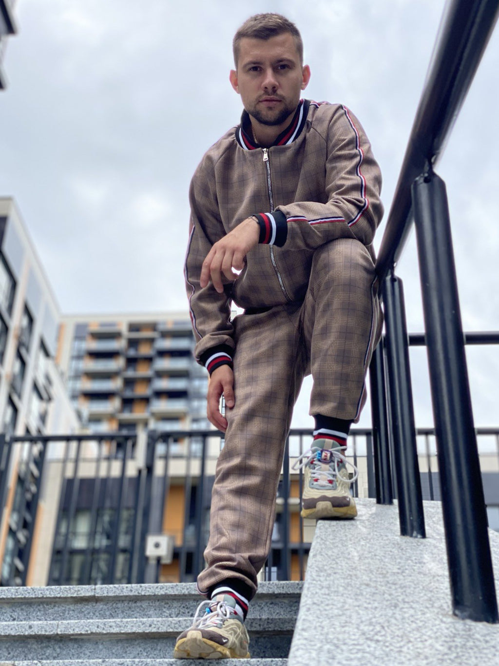 Camel Coach Gentlemen Tracksuit — posed with one foot raised; the Coach look inspired by Colin Farrell in The Gentlemen