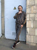 Brown Checkered Tracksuit — checkered bomber jacket and joggers inspired by The Gentlemen, leaning against a wall
