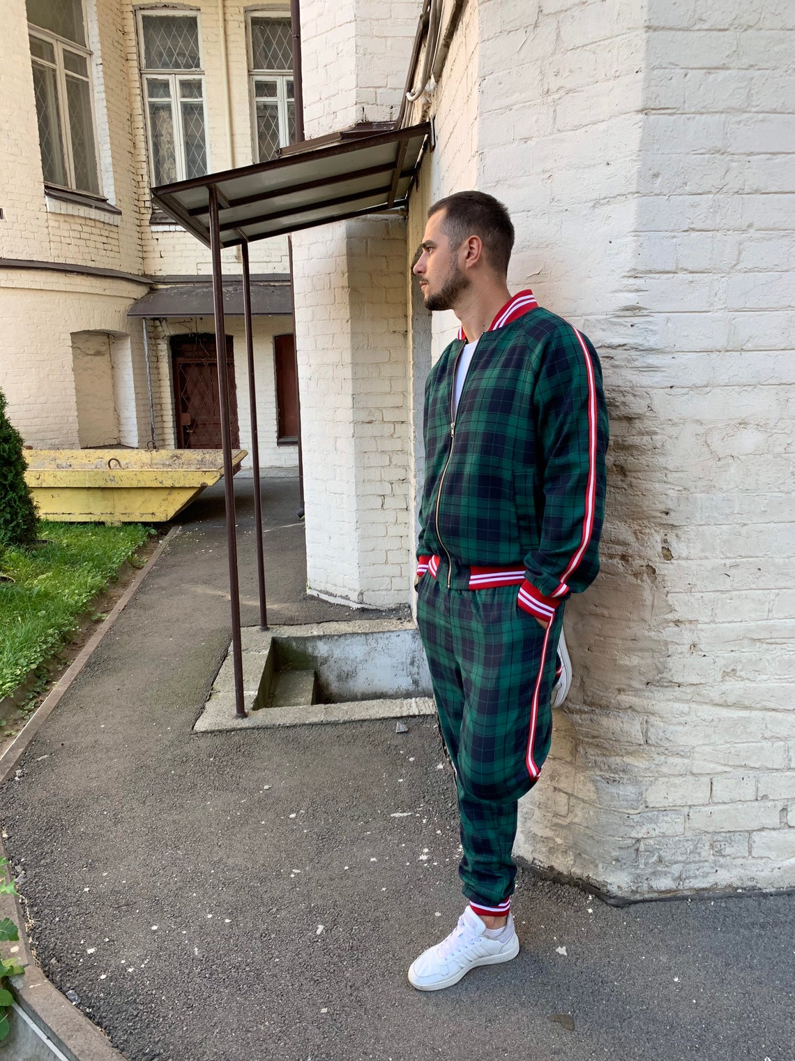Premium Green Tartan Coach Gentlemen Tracksuit — tartan bomber jacket and joggers, leaning against a wall